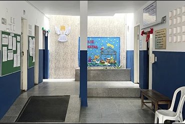 Hall de entrada do colégio, com murais nas paredes e área de espera