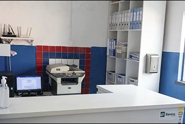 Balcão da secretaria do colégio, com computador, impressora e arquivos organizados